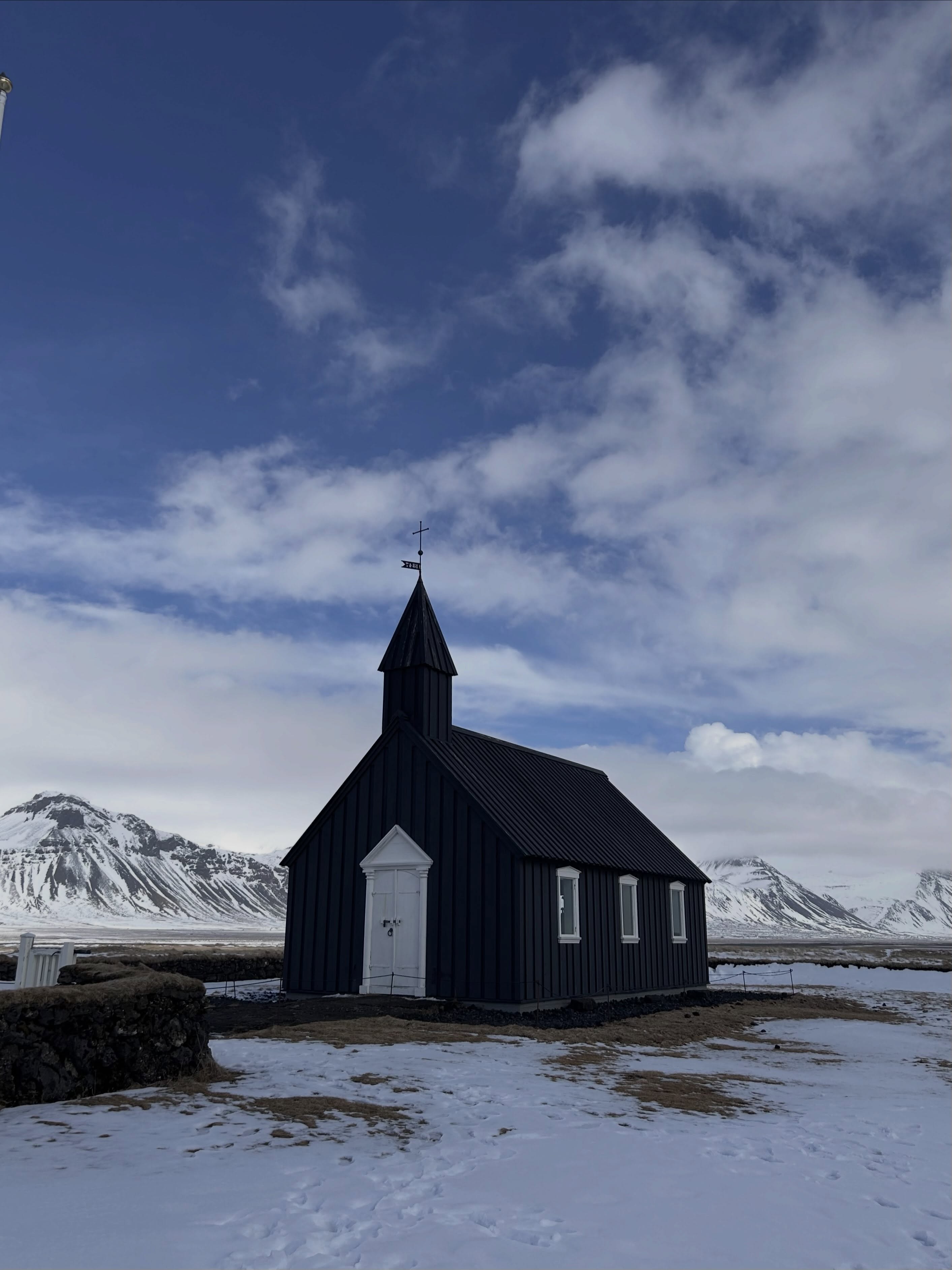 A small black church stands in snow beneath a deep blue sky.